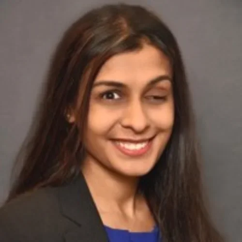 Headshot of Preeti Kakani smiling with a gray background.