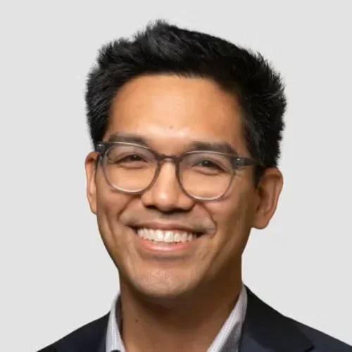 Headshot of Carlos Oronce smiling with a white background