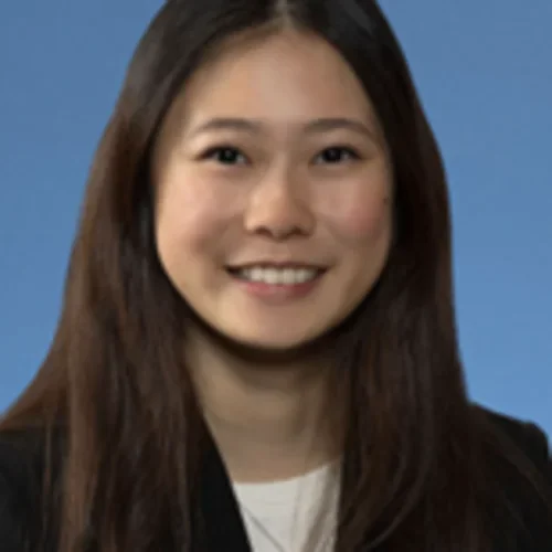 Angela wearing business attire, smiling with a solid blue background