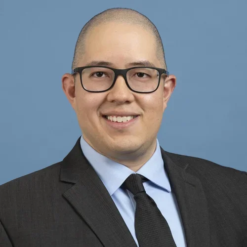 Headshot of Chad Villaflores smiling and wearing a suit with a blue background