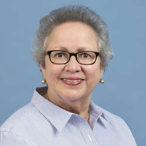 Headshot of Carmen E. Reyes smiling with a blue background