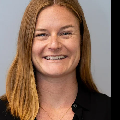 Headshot of Zoe Trutner smiling with a gray background.