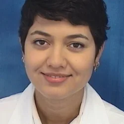 Headshot of  Alast Ahamdi smiling with a blue background.