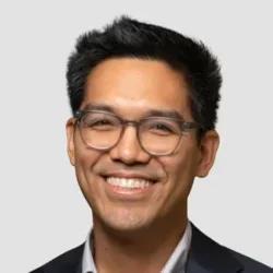 Headshot of Carlos Oronce smiling with a white background