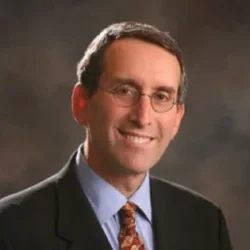 Headshot of Daniel Wolfson smiling with a gray background