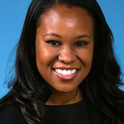 Headshot of Folasade P. May, MD, PhD, MPhil, smiling with a light gray background