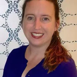 Headshot of Anne M. Walling, MD, PhD, FAAHPM, smiling against a background with a patterned design